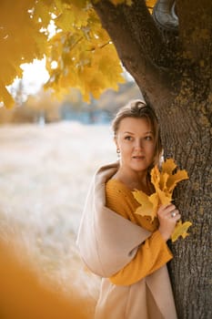 Woman holding autumn leafs in the nature. Autumn woman on leafs background.
