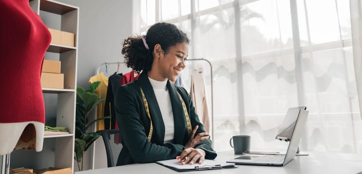 portrait smile black woman working on clothes in tailoring atelier. Attractive beautiful young female fashion designer smile after success in make new handmade suit in workshop...