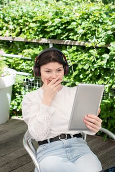 candid portrait of a young woman chatting through a tablet with headphones outdoor. High quality photo