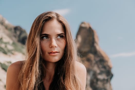 Woman travel sea. Young Happy woman in a long red dress posing on a beach near the sea on background of volcanic rocks, like in Iceland, sharing travel adventure journey