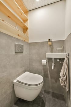 a bathroom with a toilet, sink and towel hanging on the wall next to it is a wooden shelf above the toilet