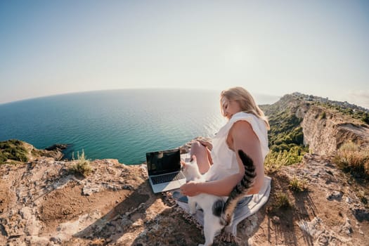 Woman sea laptop. Business woman in yellow hat working on laptop by sea. Close up on hands of pretty lady typing on computer outdoors summer day. Freelance, digital nomad, travel and holidays concept.