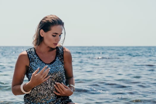 Woman travel sea. Young Happy woman in a long red dress posing on a beach near the sea on background of volcanic rocks, like in Iceland, sharing travel adventure journey