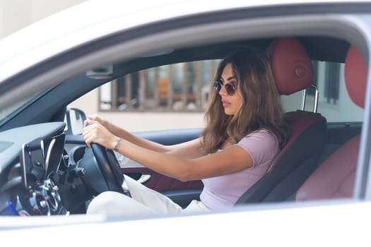 Beautiful young happy smiling woman driving her expensive luxury car, serious focused face