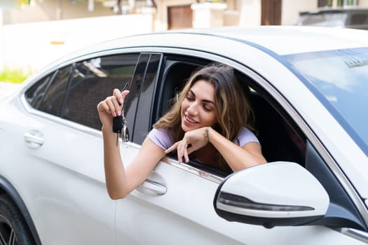 Beautiful young happy smiling woman driving her car, showing the keys to a new car