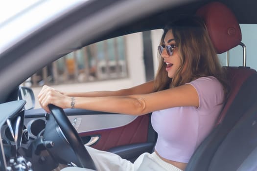 Beautiful young happy smiling woman driving her expensive luxury car, traveling, excited