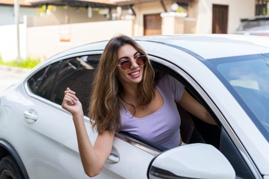 Beautiful young happy smiling woman driving her car, sitting behind the wheel, looking out the window