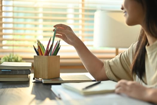 Cropped image of teenage asian woman doing homework, preparing for exam at home. Education concept.