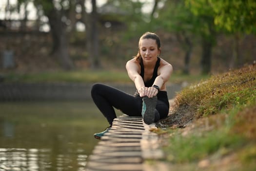 Sporty woman sporty woman stretching exercises near lake. Healthy lifestyle, sport and fitness concept.