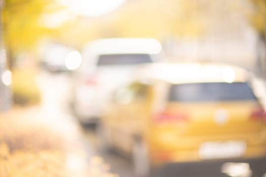 Autumn season bokeh background. Abstract city blur along the road with cars