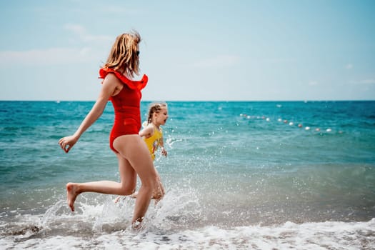 Happy loving family mother and daughter having fun together on the beach. Mum playing with her kid in holiday vacation next to the ocean - Family lifestyle and love concept.