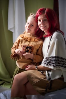 Amazing pretty mother and daughter having fun together. Red haired mom and small little blonde girl hugging and having lovely free time on white background in studio