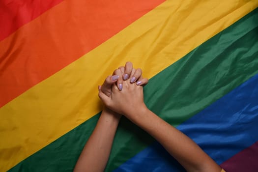Two women lesbian couple holding hands over LGBT pride flag. LGBT concept.