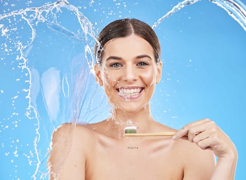 Woman with water splash, dental hygiene and toothbrush with smile, toothpaste and for brushing teeth. Oral health, female and lady clean mouth, fresh breath and healthy on blue studio background