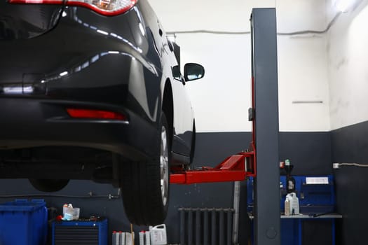 Modern car on lift in service center. Car insurance and repair service concept