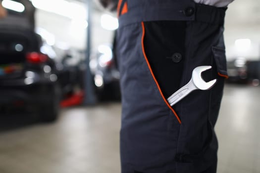 Wrench in pocket in uniform at locksmith in auto repair shop. Tool in special work clothes and car maintenance