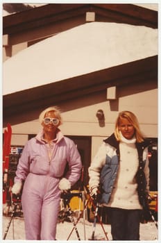 THE ALPS, SWITZERLAND - 1982: Vintage photo shows mother and daughter on winter vacation at the ski resort.