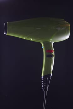 Green modern stylish hair dryer on black background. Choosing quality hair dryer for drying and styling hair concept
