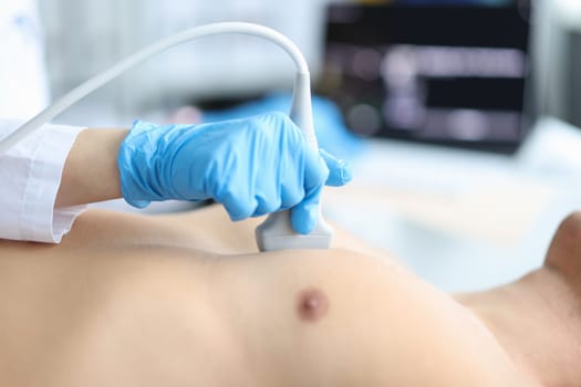 Doctor makes echocardiography of male patient using ultrasound probe pressing on patient chest. Ultrasound of heart in man concept