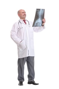 Front view of a senior doctor with stethoscope studying x-ray image. Isolated on white background