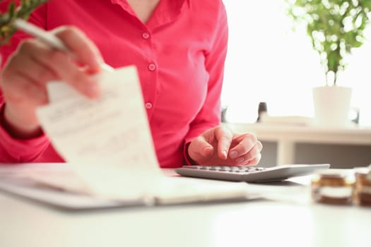 Woman hands holding calculator and paid check closeup. Working as financial secretary and family and business budget expenses