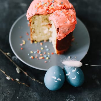 Plate with tasty Easter cake, eggs and willow branches on dark background. High quality photo