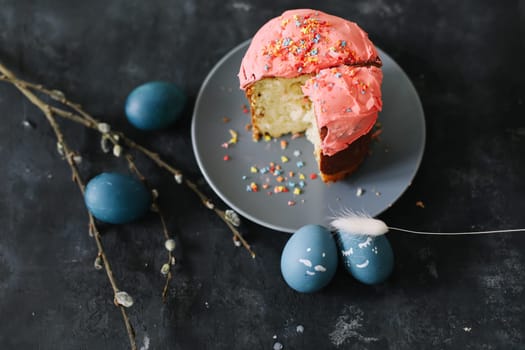 Plate with tasty Easter cake, eggs and willow branches on dark background. High quality photo