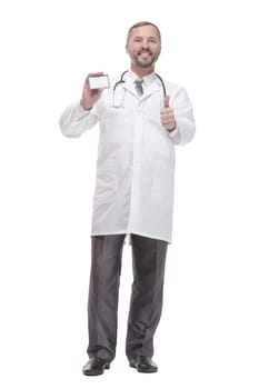 in full growth. smiling doctor showing his visiting card . isolated on a white background.