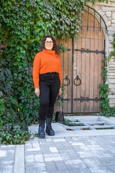 Portrait of carefree young woman smiling with urban background. Cheerful latin girl wearing eyeglasses in the city. Happy brunette woman with curly hair spectacles smiling.