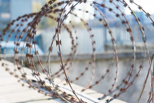 Barbered wire over blue sky and on building ground, rusty