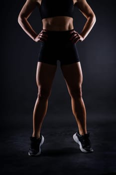 Shaped female legs in sneakers sculpted muscles, dark background