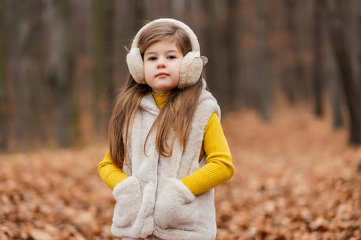 little girl in headphones walks through the autumn forest