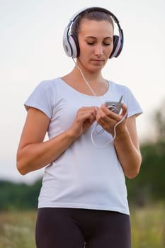 woman in headphones outdoors listening to music using phone