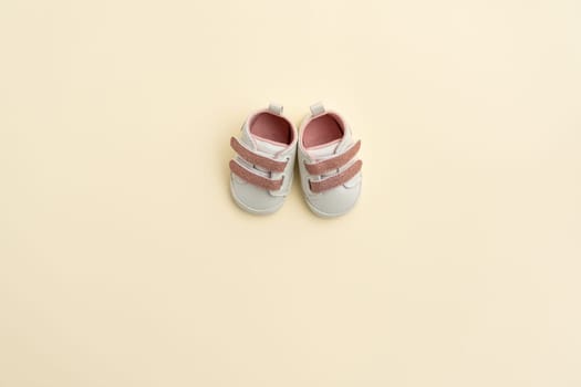 Tiny newborn baby shoes on paper background with copy space. Baby clothes concept. Top view, flat