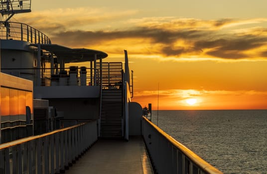 Sun setting over the water horizon with a cruise ship in the foreground