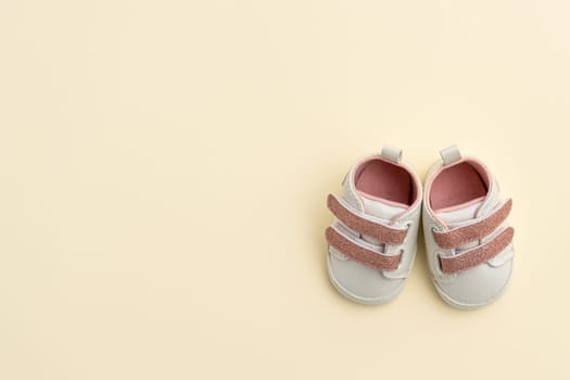 Tiny newborn baby shoes on paper background with copy space. Baby clothes concept. Top view, flat