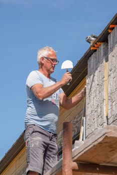 the bricklayer makes the facade of the house from gray bricks with cement and plaster at the construction site. High quality photo