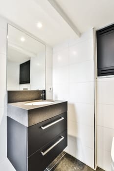 a black and white bathroom with a sink, mirror, and television on the wall in the corner of the room