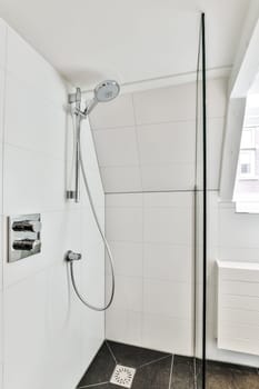 a modern bathroom with white tile walls and black flooring, including a shower head in the wall is tiled