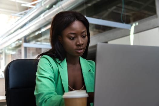 Young African American female works concentrated using laptop in the office. Business concept.
