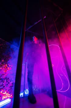 Caucasian woman in neon studio behind steel bars