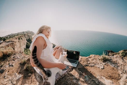 Woman sea laptop. Business woman in yellow hat working on laptop by sea. Close up on hands of pretty lady typing on computer outdoors summer day. Freelance, digital nomad, travel and holidays concept.