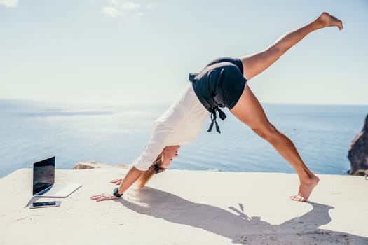 Happy girl doing yoga with laptop working at the beach. beautiful and calm business woman sitting with a laptop in a summer cafe in the lotus position meditating and relaxing. freelance girl remote work beach paradise