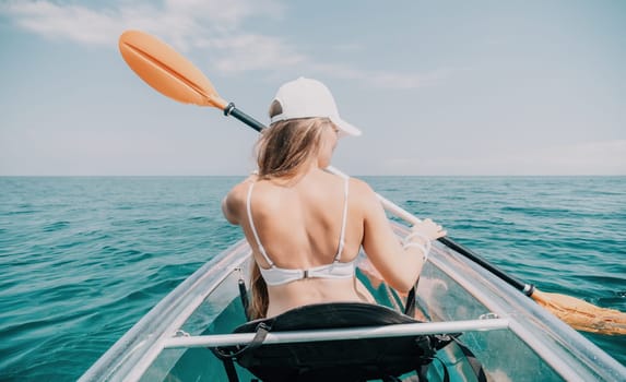 Woman in kayak back view. Happy young woman with long hair floating in transparent kayak on the crystal clear sea. Summer holiday vacation and cheerful female people having fun on the boat.