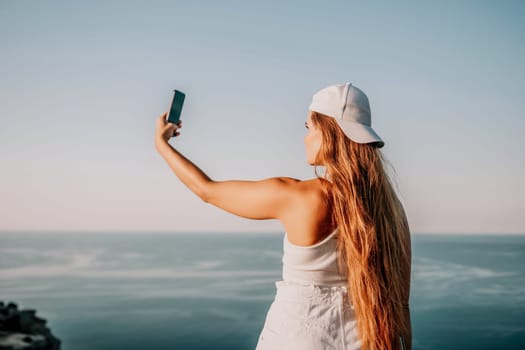Woman travel sea. Young Happy woman in a long red dress posing on a beach near the sea on background of volcanic rocks, like in Iceland, sharing travel adventure journey