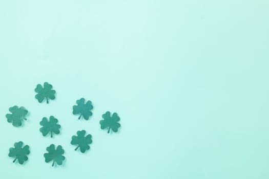 Happy St. Patrick's Day decoration background. Flat lay of cutting paper clover leaves festive decor, shamrocks leaves holiday symbol with copy space on colour background, Banner greeting card concept