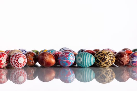 Composition of Easter eggs set in a row on a solid white background. The set Easter decoration is reflected in the glass.