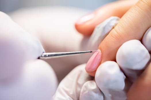 The beautician wears disposable nitrile gloves. Maintaining the rules of hygiene in the beauty salon. Performing a hybrid manicure on a natural nail plate.