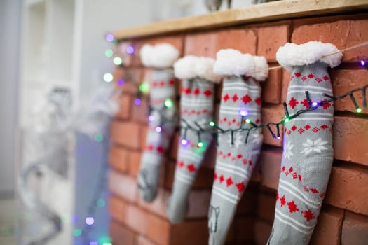Brick fireplace with Christmas socks and Christams lights. Warm woolen socks.