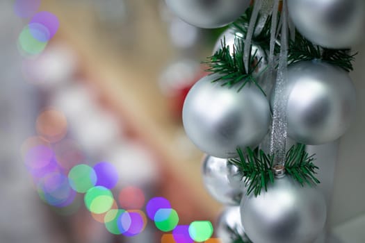 Silver baubles on spruce twigs and decorated fireplace in background.